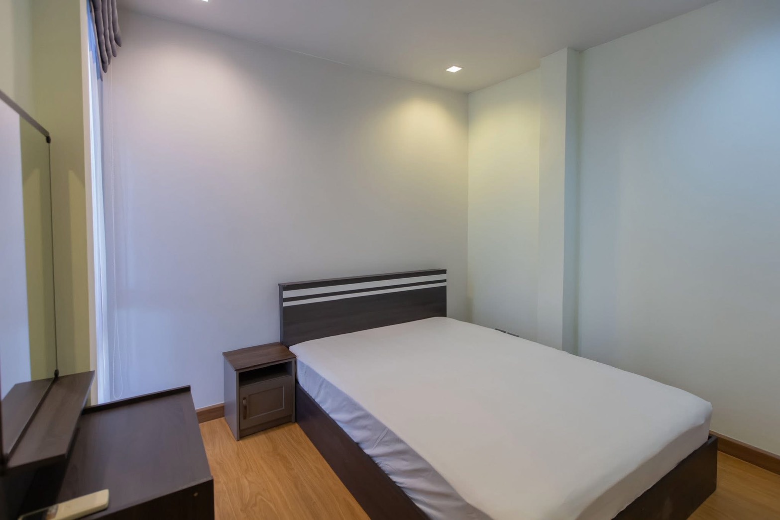 独立式住宅 出租在Lat Phrao, Bangkok - 简约客卧，双人床、木地板、床头柜与梳妆台。