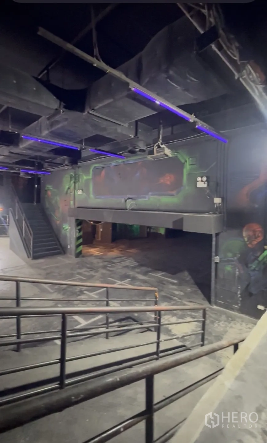 零售空间 出租在Khlong Toei, Bangkok - 黑色吊顶下的坡道和夹层，点缀蓝色灯光。