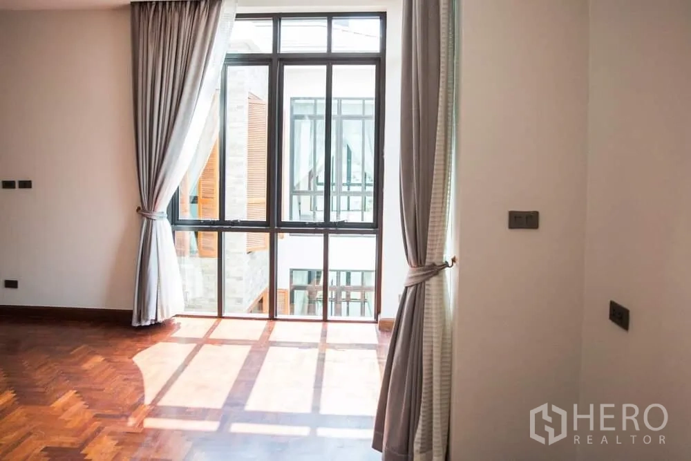 บ้าน ให้เช่าในKhlong Toei, Bangkok - ห้องนอนรับแสงธรรมชาติ ผ้าม่านสีเทา หน้าต่างบานใหญ่หันสู่คอร์ทยาร์ดภายใน