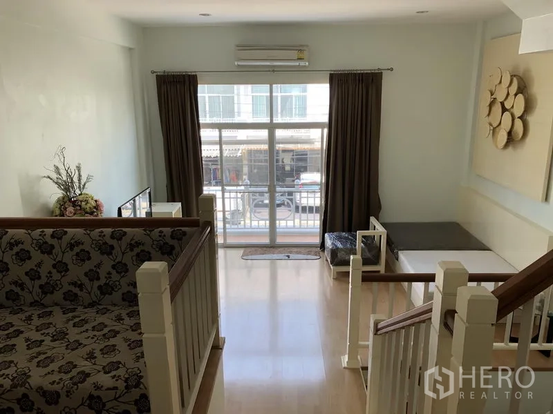 联排别墅 出租在Prawet, Bangkok - 楼上起居区，木地板，大窗与通阳台的玻璃门。