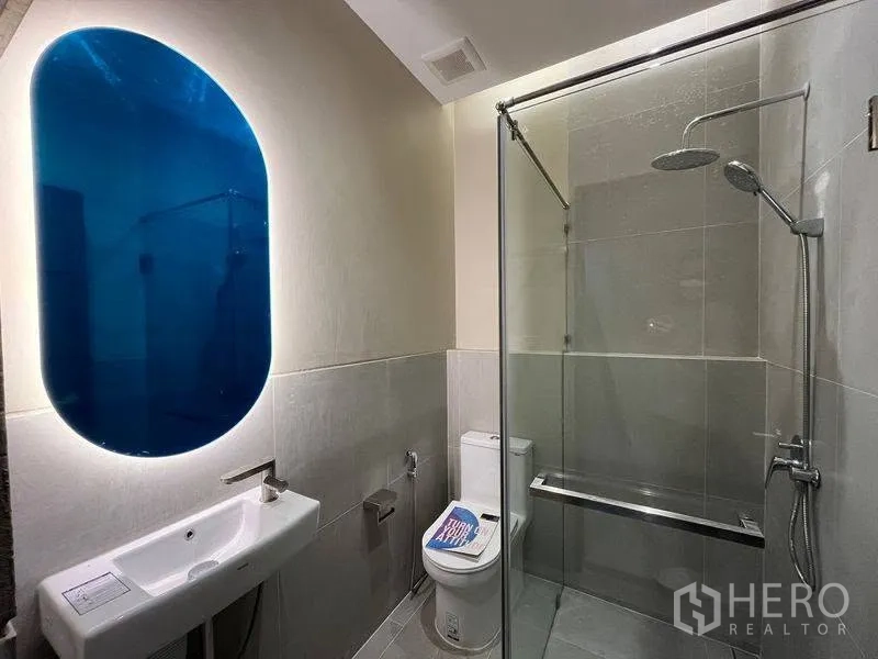联排别墅 for rent in Phra Khanong, Bangkok - 现代卫浴，蓝色背光镜、玻璃淋浴房与马桶。