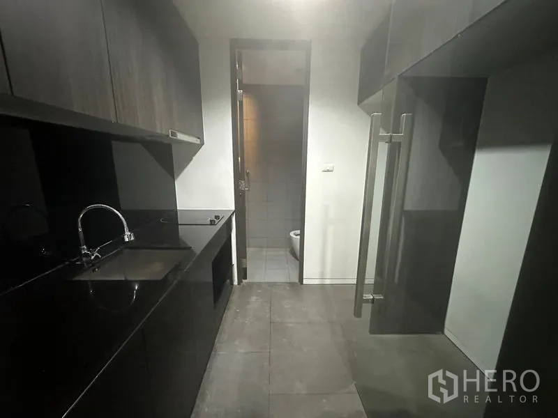 สำนักงาน ให้เช่า - แพนทรีสำนักงานโทนเข้มพร้อมอ่างล้างมือ เตาและตู้เก็บของ ถัดไปเป็นประตูเข้าห้องน้ำ