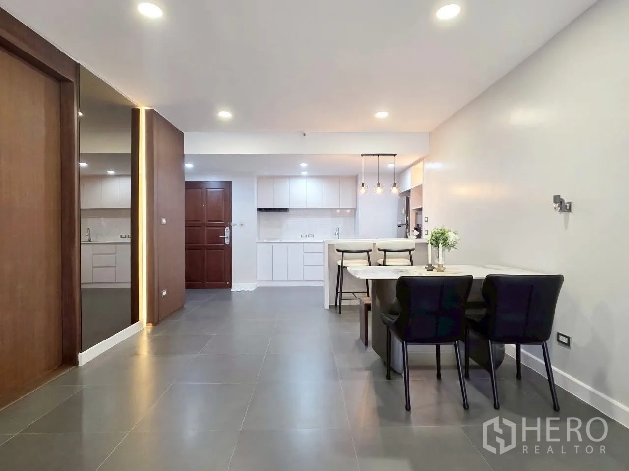 Condominium for rent in Sathon, Bangkok - Dining area and entryway connected to a minimalist white kitchen.