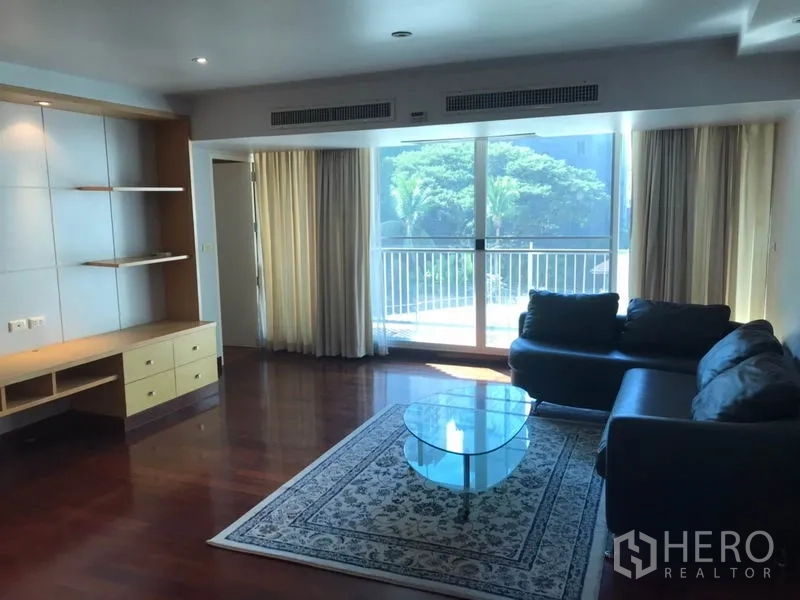 คอนโด ให้เช่าในWatthana, Bangkok - ห้องนั่งเล่นโปร่ง พื้นไม้ โซฟา โต๊ะกระจก และประตูระเบียงวิวต้นไม้