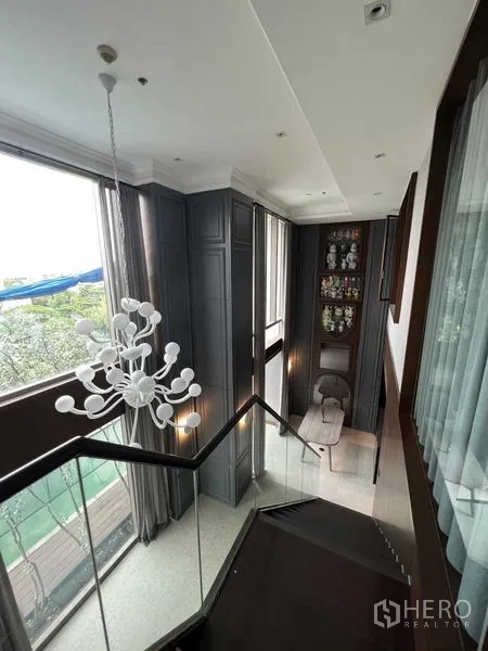 公寓 出售在Khlong Toei, Bangkok - 楼梯平台，玻璃栏杆、吊灯与靠窗展示柜。