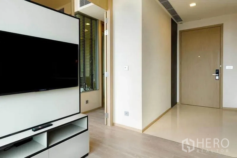 Condominium for rent or sale in Watthana, Bangkok - Entry hall with TV console facing living space and door to the bedroom.