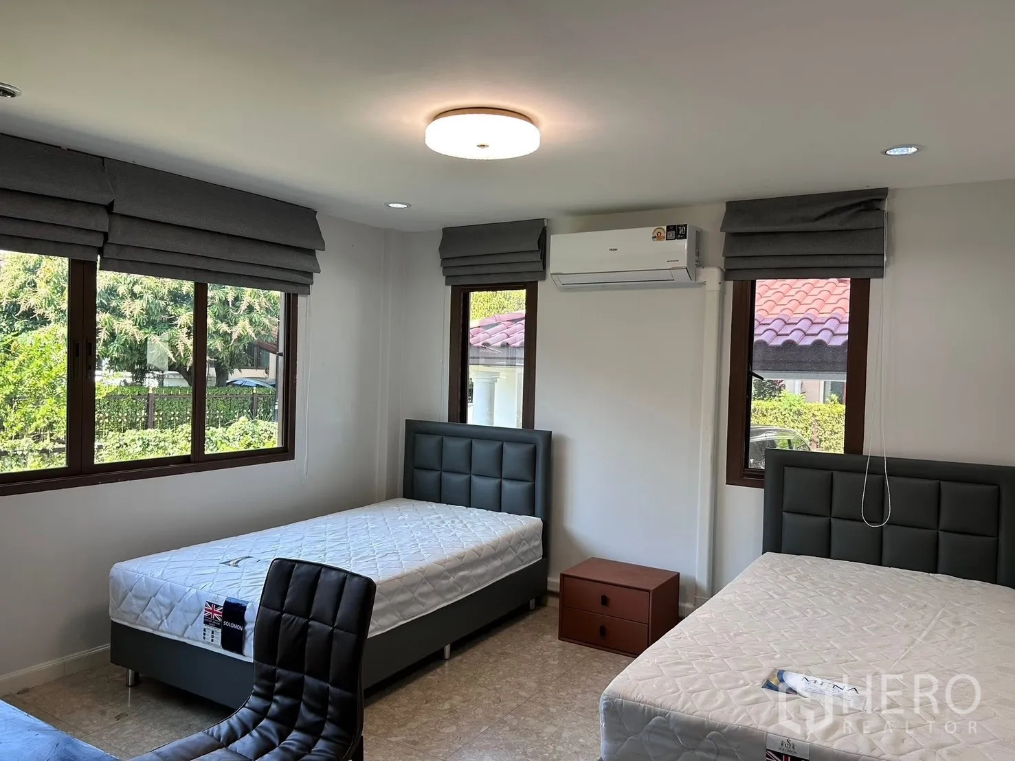 บ้าน ให้เช่าในLat Krabang, Bangkok - ห้องนอนเตียงคู่สว่าง หน้าต่างบานใหญ่ ม่านพับสีเทา แอร์ และเก้าอี้ทำงาน