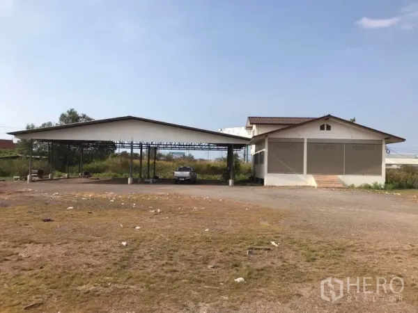 Land for sale in Mueang Samut Sakhon, Samut Sakhon - Open yard with roofed shed and raised office building set back from the road.