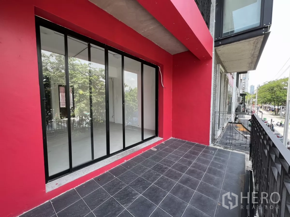 零售空间 出租在Khlong Toei, Bangkok - 二层露台，黑色地砖与整面玻璃门，俯瞰树木与街道。