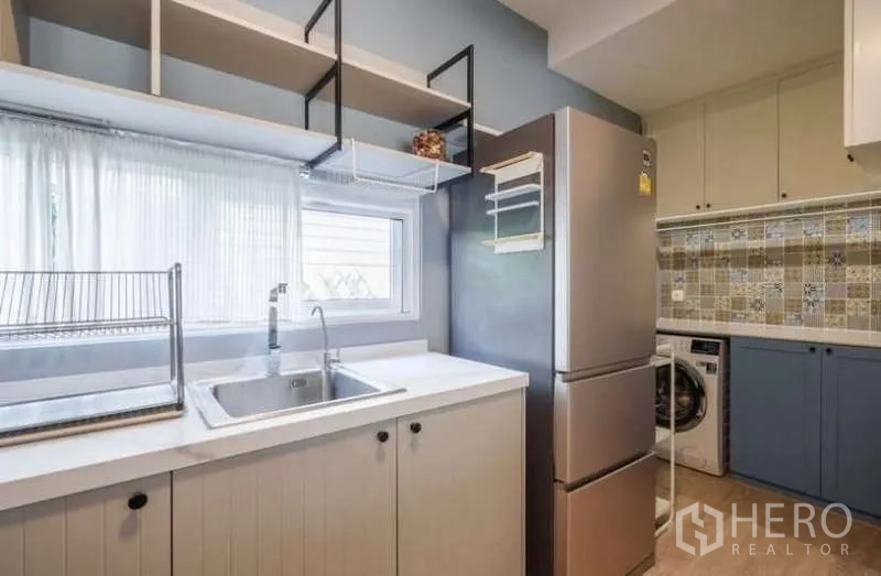 Detached House for rent in Prawet, Bangkok - Service kitchen with sink, open shelving, fridge and laundry area with patterned backsplash.