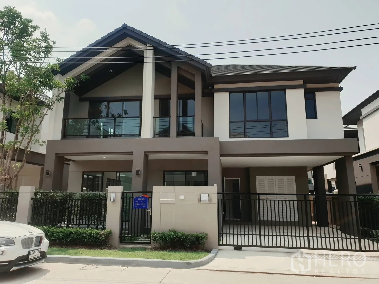 บ้านเดี่ยว for rent in Saphan Sung, Bangkok - มุมมองด้านหน้ากว้างของบ้านเดี่ยวสมัยใหม่ พร้อมทางรถและประตูรั้วเหล็ก.