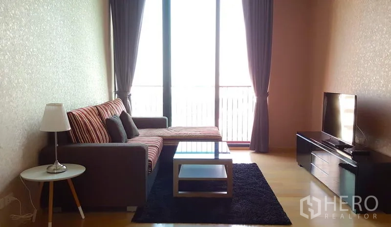 คอนโด ให้เช่าในPhaya Thai, Bangkok - ห้องนั่งเล่น โซฟาเข้ามุม โต๊ะกลางกระจก ชั้นวางทีวี และหน้าต่างสูงจรดเพดาน