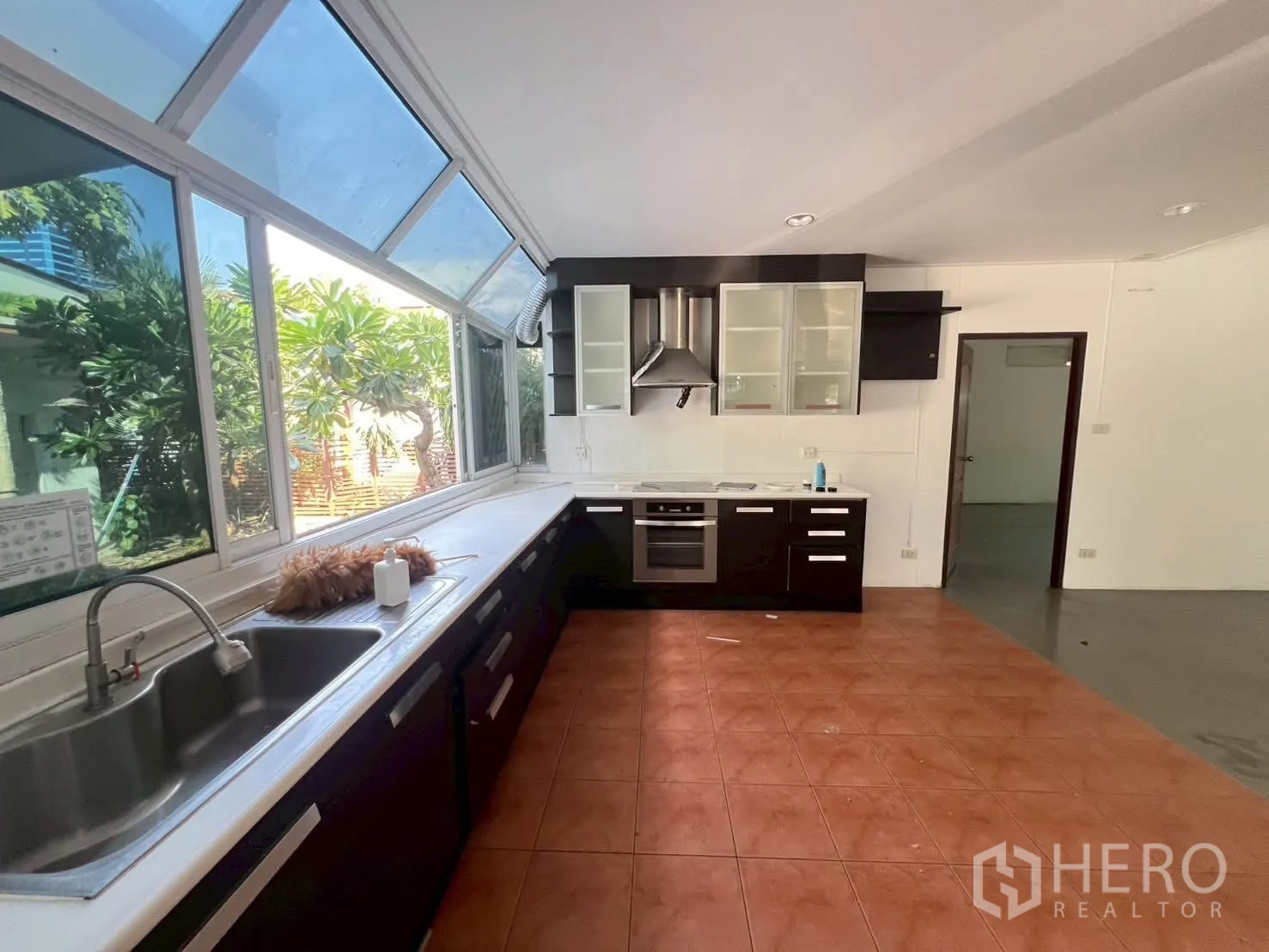 Detached House for rent in Watthana, Bangkok - Kitchen with long countertops, sink, built-in oven, range hood, and big windows.