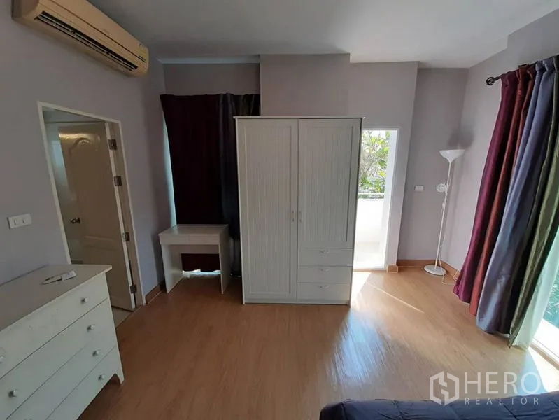 Condominium for sale in Wang Thonglang, Bangkok - Air-conditioned bedroom with wardrobe, desk and balcony access.