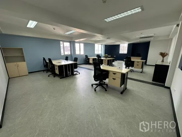 Office Space for rent in Watthana, Bangkok - Modular desks and task chairs arranged in a bright workspace with ceiling lights and a storage shelf.