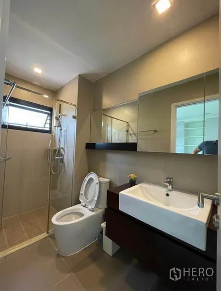 Townhouse for rent in Yan Nawa, Bangkok - Bathroom with glass shower, large mirror, and modern sanitaryware.