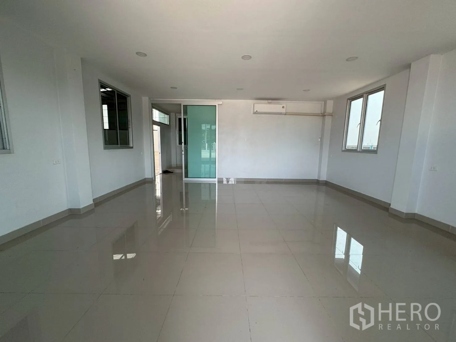 Warehouse for rent in Phutthamonthon, Nakhon Pathom - Unfurnished office room with glossy tiled floors, windows and a wall-mounted air conditioner.