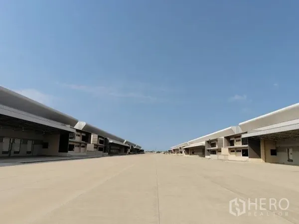 Factory for rent in Bang Pakong, Chachoengsao - Wide driveway between warehouse buildings with shaded loading bays for trailer access.
