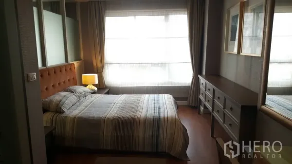 คอนโด ให้เช่าในKhlong Toei, Bangkok - ห้องนอนอบอุ่นพร้อมหัวเตียงบุผ้า โคมไฟข้างเตียง หน้าต่างกว้าง และตู้ลิ้นชักยาว