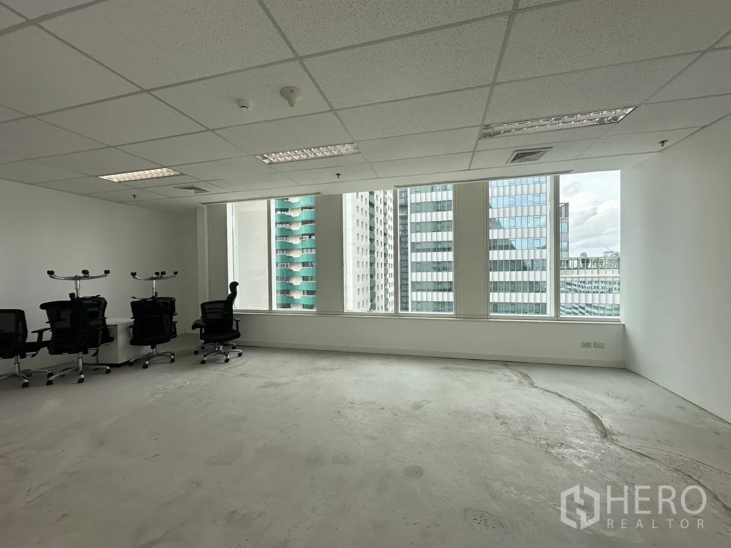 ออฟฟิศ for rent in Watthana, Bangkok - สำนักงานแบบเปิดโล่ง กระจกบานใหญ่ ผนังสีขาว และเก้าอี้ทำงานมองเห็นตึกสูงเมือง.