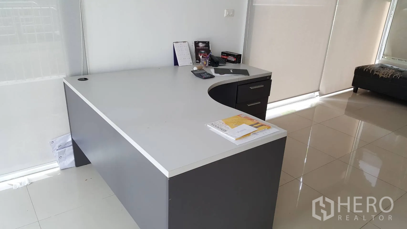 คอนโด ให้เช่าในPathum Wan, Bangkok - มุมทำงานเรียบร้อยพร้อมโต๊ะรูปตัวแอล เครื่องคิดเลข และมู่ลี่ม้วนริมหน้าต่าง