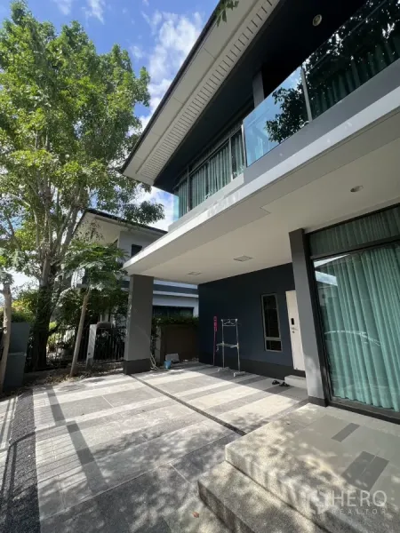 บ้าน ให้เช่าในBang Kapi, Bangkok - ที่จอดรถมีหลังคาและเฉลียงหน้าบ้าน ใต้ระเบียงยื่น พร้อมบรรยากาศสวน