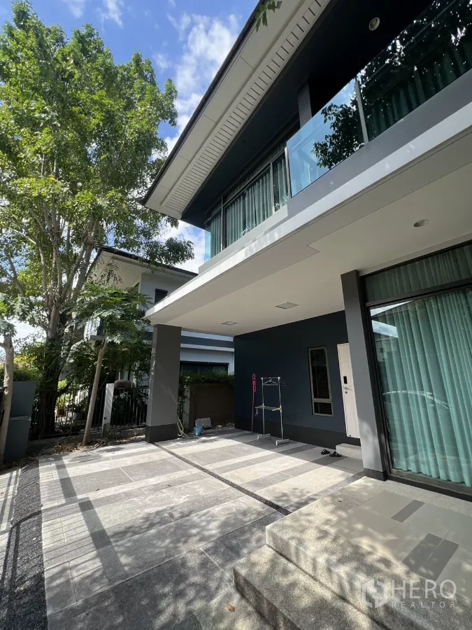 บ้าน ให้เช่าในBang Kapi, Bangkok - ที่จอดรถมีหลังคาและเฉลียงหน้าบ้าน ใต้ระเบียงยื่น พร้อมบรรยากาศสวน