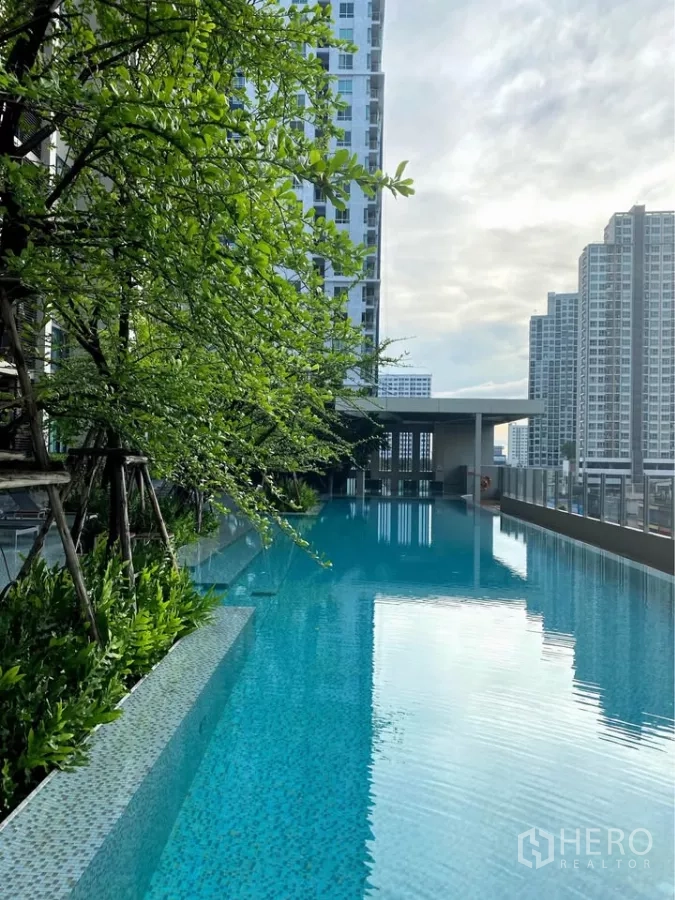 Condominium for rent in Watthana, Bangkok - Outdoor lap pool with lush greenery and high-rise backdrop.
