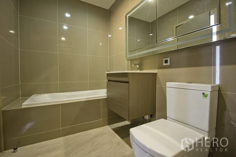 คอนโด ให้เช่าในWatthana, Bangkok - ห้องน้ำที่สองมีอ่างอาบน้ำ ตู้กระจก เคาน์เตอร์ล้างหน้า และโถสุขภัณฑ์ โทนสีเบจ