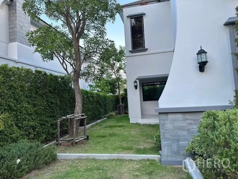 Detached House for sale in Taling Chan, Bangkok - Side garden with lawn, mature tree and tall privacy hedge along the boundary.