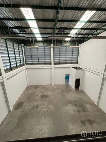 Warehouse for rent in Phra Samut Chedi, Samut Prakan - View from the mezzanine over the high-ceiling warehouse hall with skylights and louvered panels.
