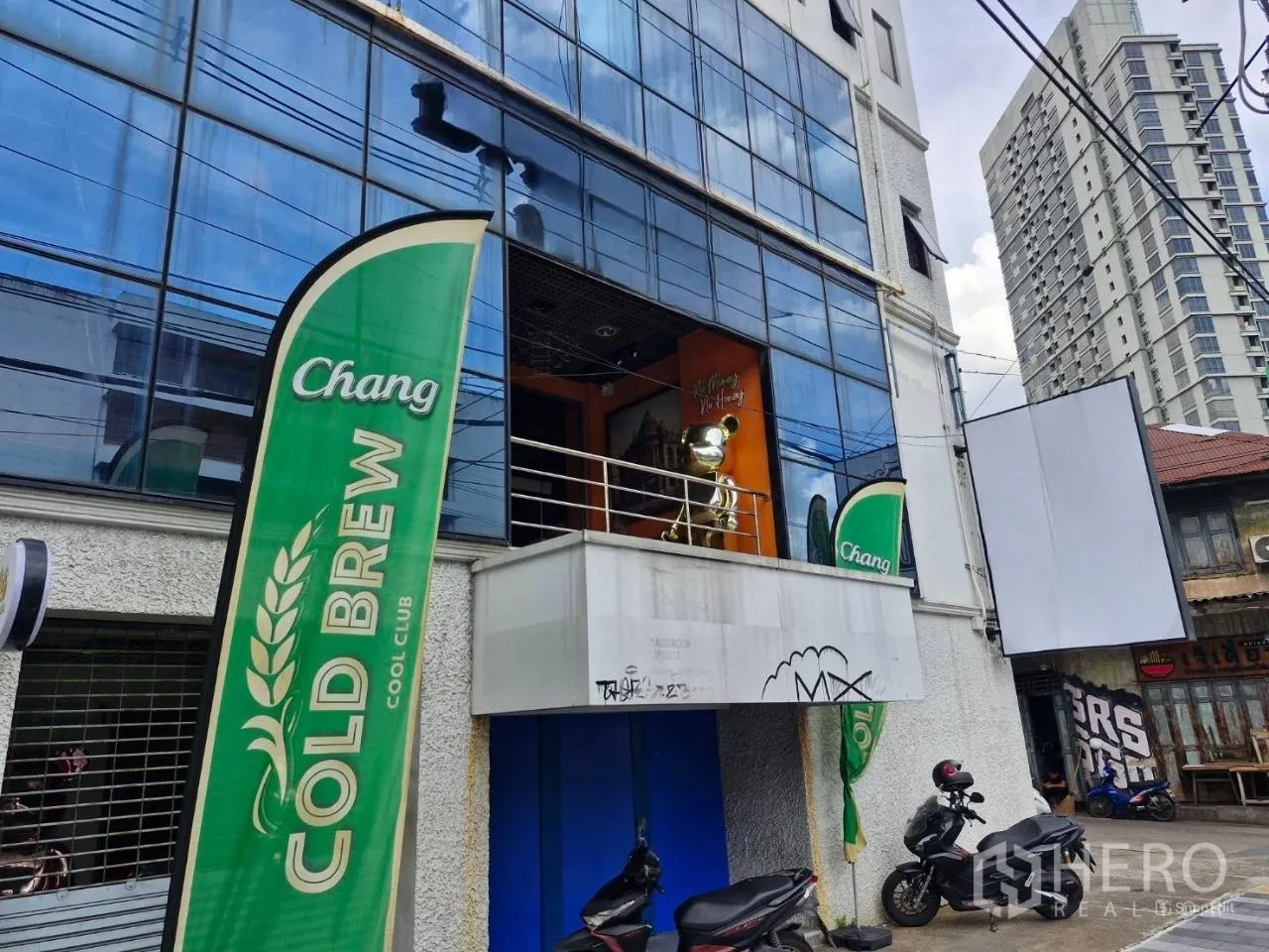 Shophouse for rent in Pathum Wan, Bangkok - Building exterior with blue glass facade and upper-floor shophouse entrance.