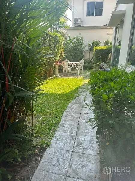 Detached House for rent in Bang Phli, Samut Prakan - Lush side garden with a stone path and white outdoor table and chairs.