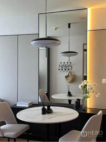 Condominium for rent in Watthana, Bangkok - Dining nook close-up featuring a marble-top round table, pendant light and mirrored wall.