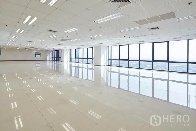 Office Space for rent in Bang Na, Bangkok - Unfurnished corner office with wall-to-wall windows, city views, reflective flooring and ceiling air-conditioning vents.