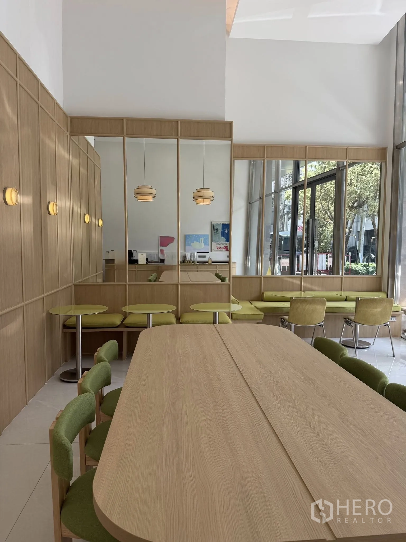 พื้นที่ขายของ for rent in Watthana, Bangkok - ภายในร้านค้าสว่าง โปร่งเพดานสูง งานไม้ เบาะสีเขียว และหน้าต่างกระจกสูงเต็มผนัง