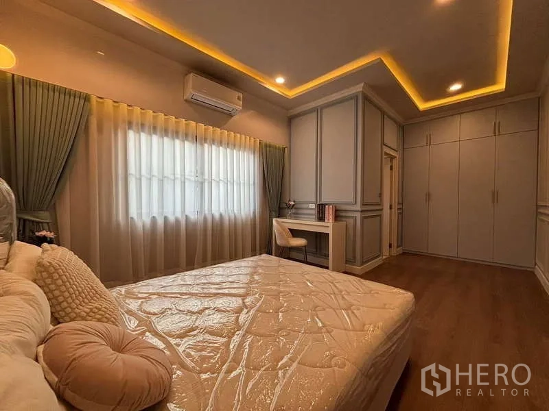 Detached House for rent in Bang Phli, Samut Prakan - Bedroom view showing built-in wardrobes, study desk and warm recessed ceiling lights.