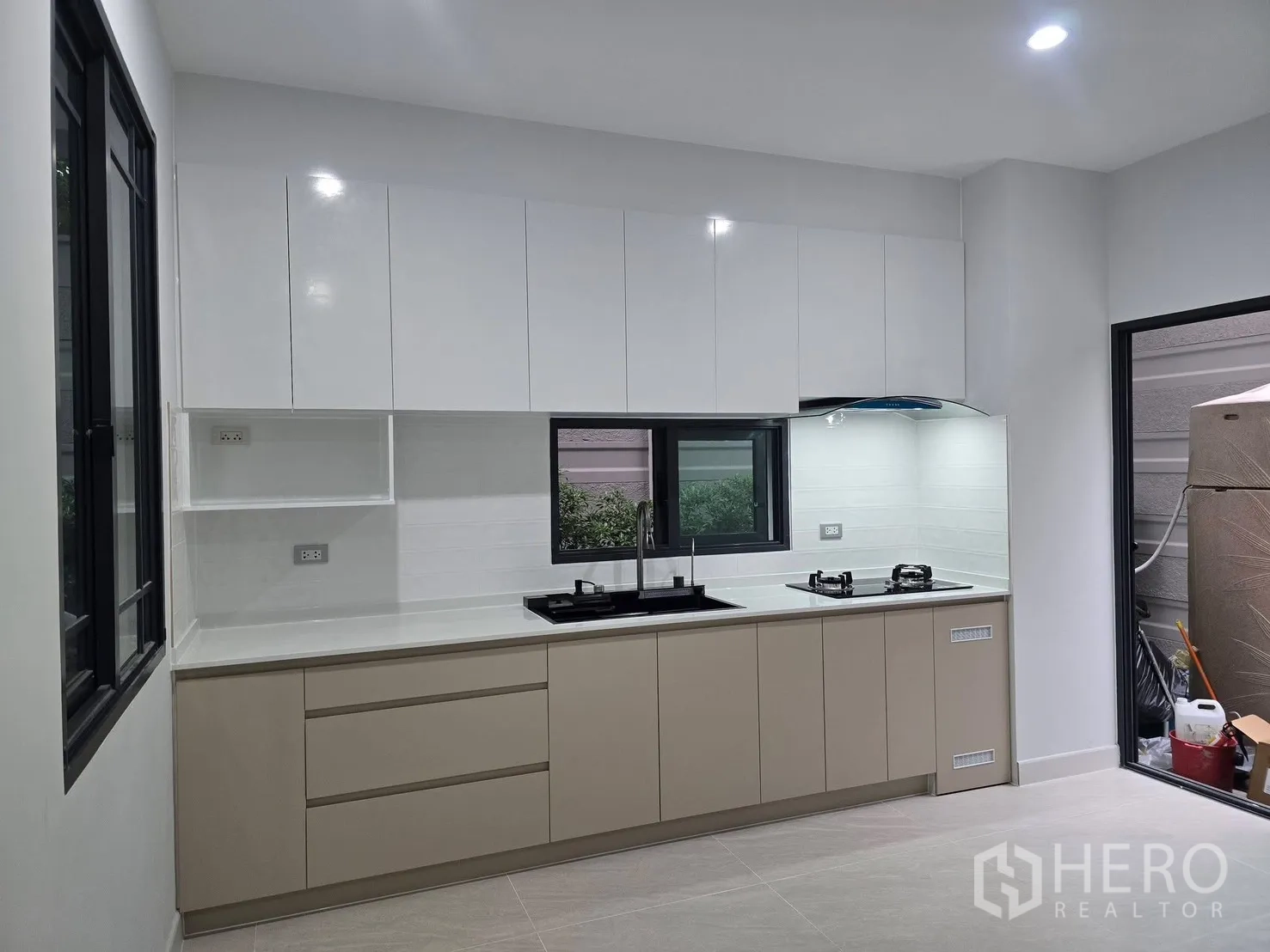 Semi-detached House for rent in Suan Luang, Bangkok - Modern built-in kitchen with white cabinets, gas hob and a window.