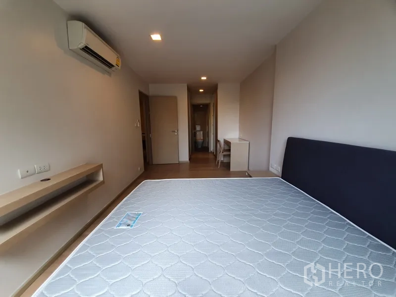 คอนโด ให้เช่าในWatthana, Bangkok - ห้องนอนพร้อมเครื่องปรับอากาศ ที่นอน โต๊ะทำงาน และทางเดินไปสู่ห้องน้ำ