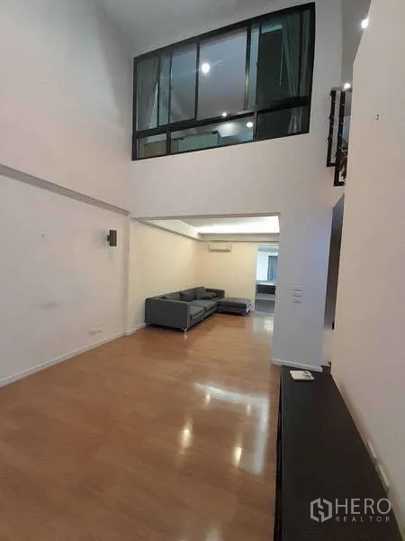 ทาวน์เฮาส์ ให้เช่าในKhlong Toei, Bangkok - โถงรับแขกกว้างมีผนังกระจกชั้นลอย พื้นไม้