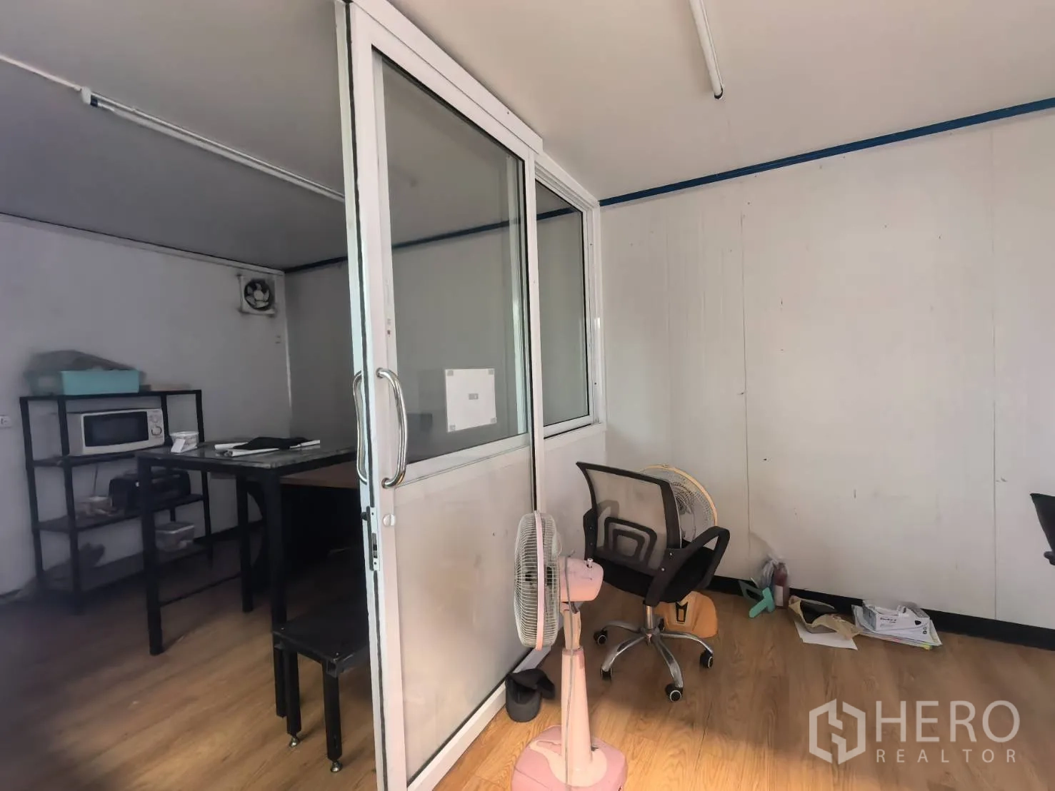 Warehouse for rent in Bang Sao Thong, Samut Prakan - Compact staff room with sliding glass door, desks, and shelving.