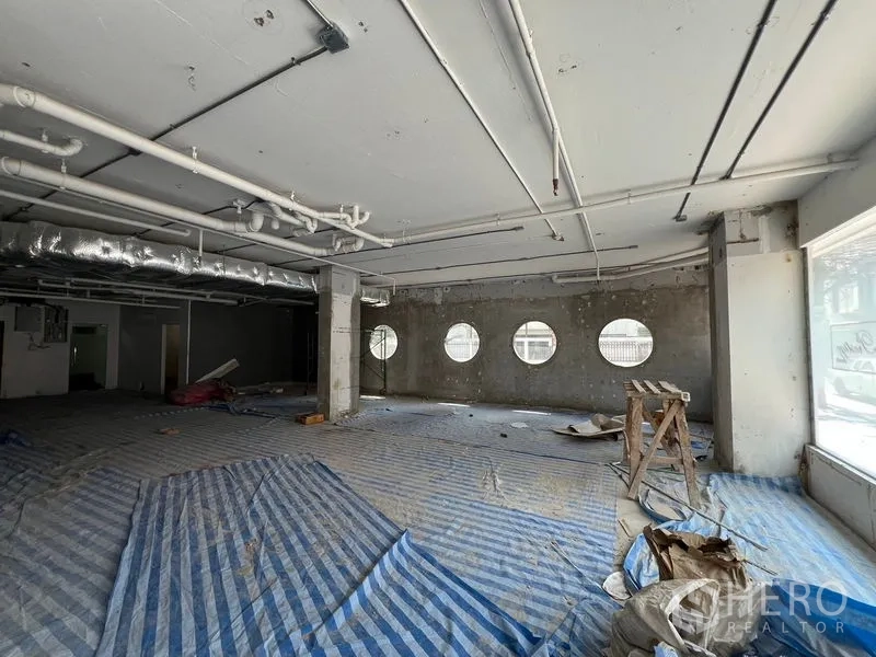 零售空间 出租在Watthana, Bangkok - 大开间厅堂，圆形窗与可见风管增强采光与通风。