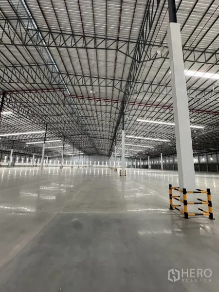 Factory for rent in Chon Buri - Open production floor under steel truss roof with LED lighting and protected columns.