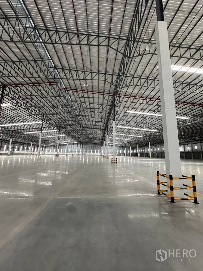 Factory for rent in Chon Buri - Open production floor under steel truss roof with LED lighting and protected columns.