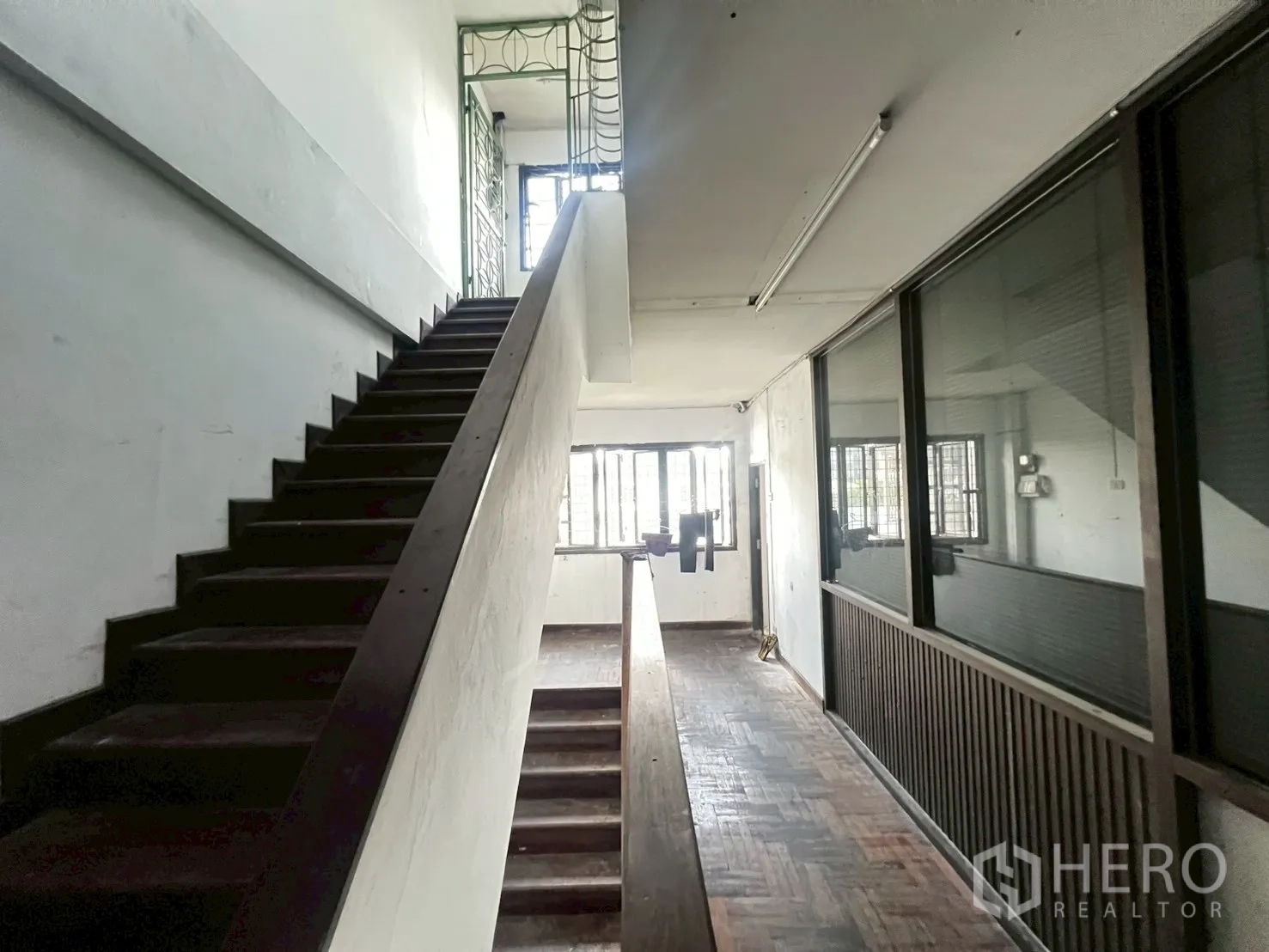 店屋 出租在Phra Khanong, Bangkok - 走廊带木楼梯、拼花地板和整面玻璃隔墙。