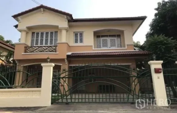 Detached House for rent in Khlong Sam Wa, Bangkok - Two-storey detached house exterior with gated driveway, covered parking and arched windows.