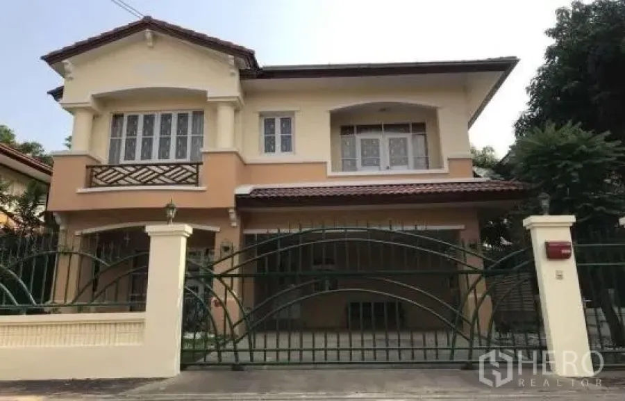 Detached House for rent in Khlong Sam Wa, Bangkok - Two-storey detached house exterior with gated driveway, covered parking and arched windows.