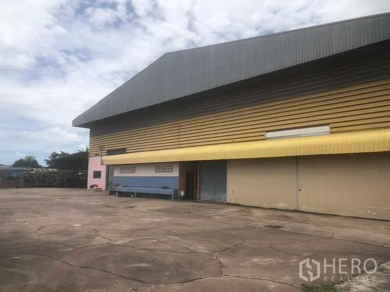 Warehouse for sale in Rayong - Expansive concrete yard in front of the warehouse with canopied entrances.