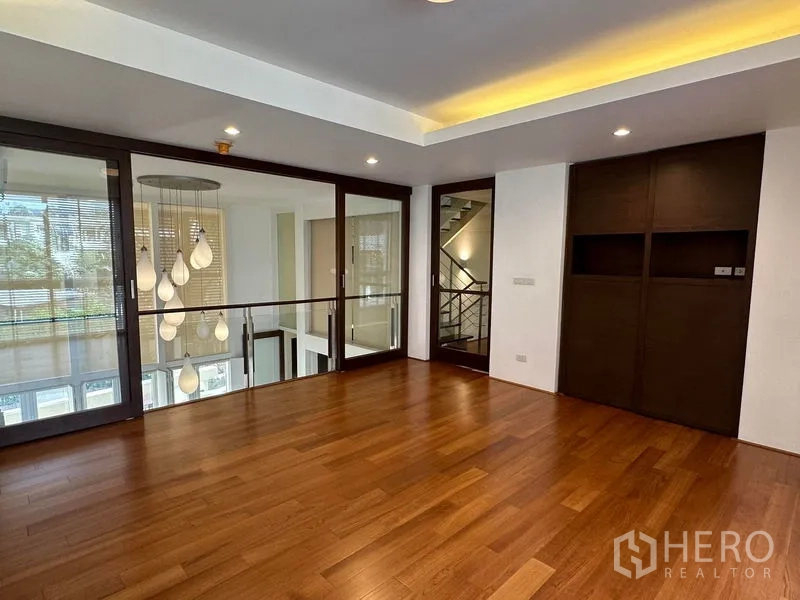 Townhouse for sale in Yan Nawa, Bangkok - Mezzanine family room with wood floors and glass balustrade overlooking double-height space