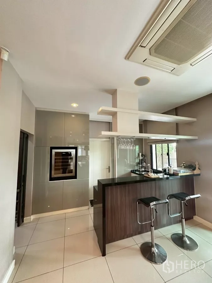 Detached House for sale in Bang Lamung, Chon Buri - Bar pantry with stone countertop, hanging glass rack and two stools.